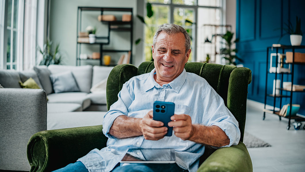 Man on green couch with tablet checking phone
